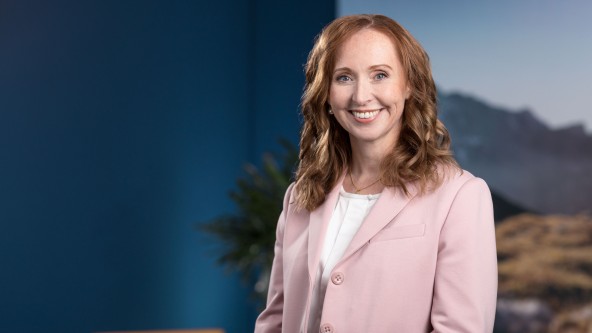 Frau mit hellbraunen Haaren und rosa Blazer lächelt