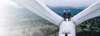 2 Personen stehen auf einem Windrad ganz oben und blicken auf die Natur